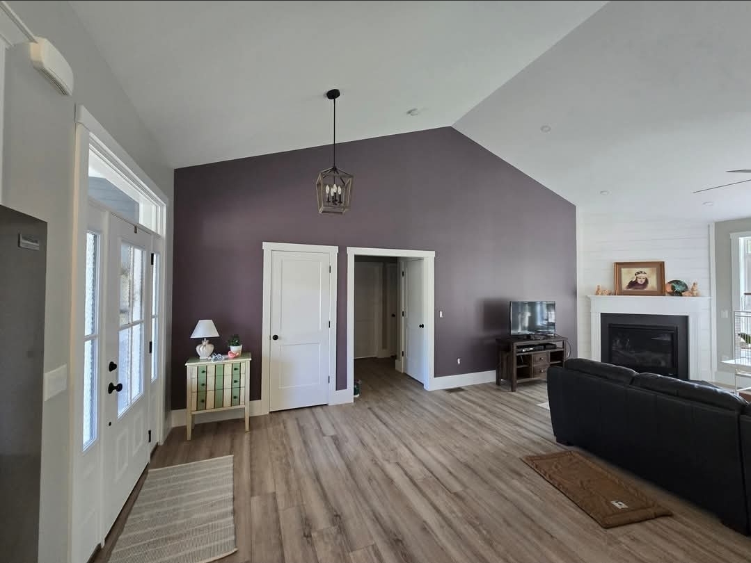 Living room with a deep purple accent wall, fresh trim paint and new flooring