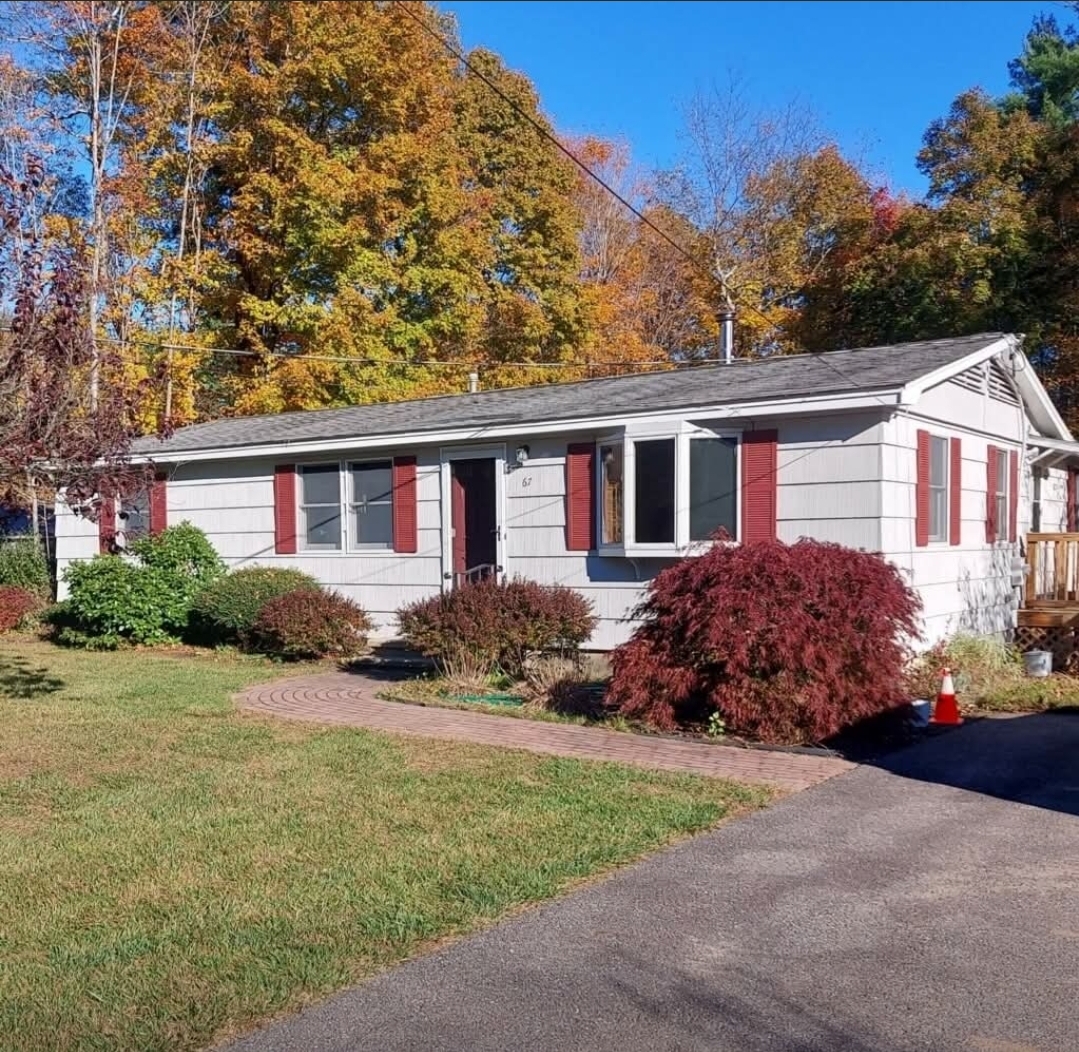 Exterior of a light gray ranch home with freshly painted red shutters