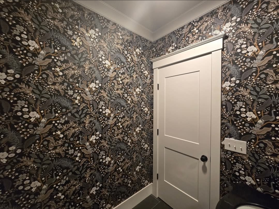 Powder room with dark floral wallpaper and crisp white trim